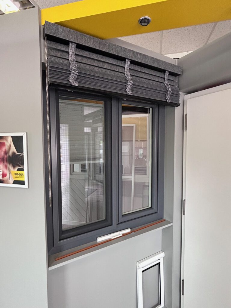 Ein Doppelfenster mit einer dunkelgrauen Innenjalousie.