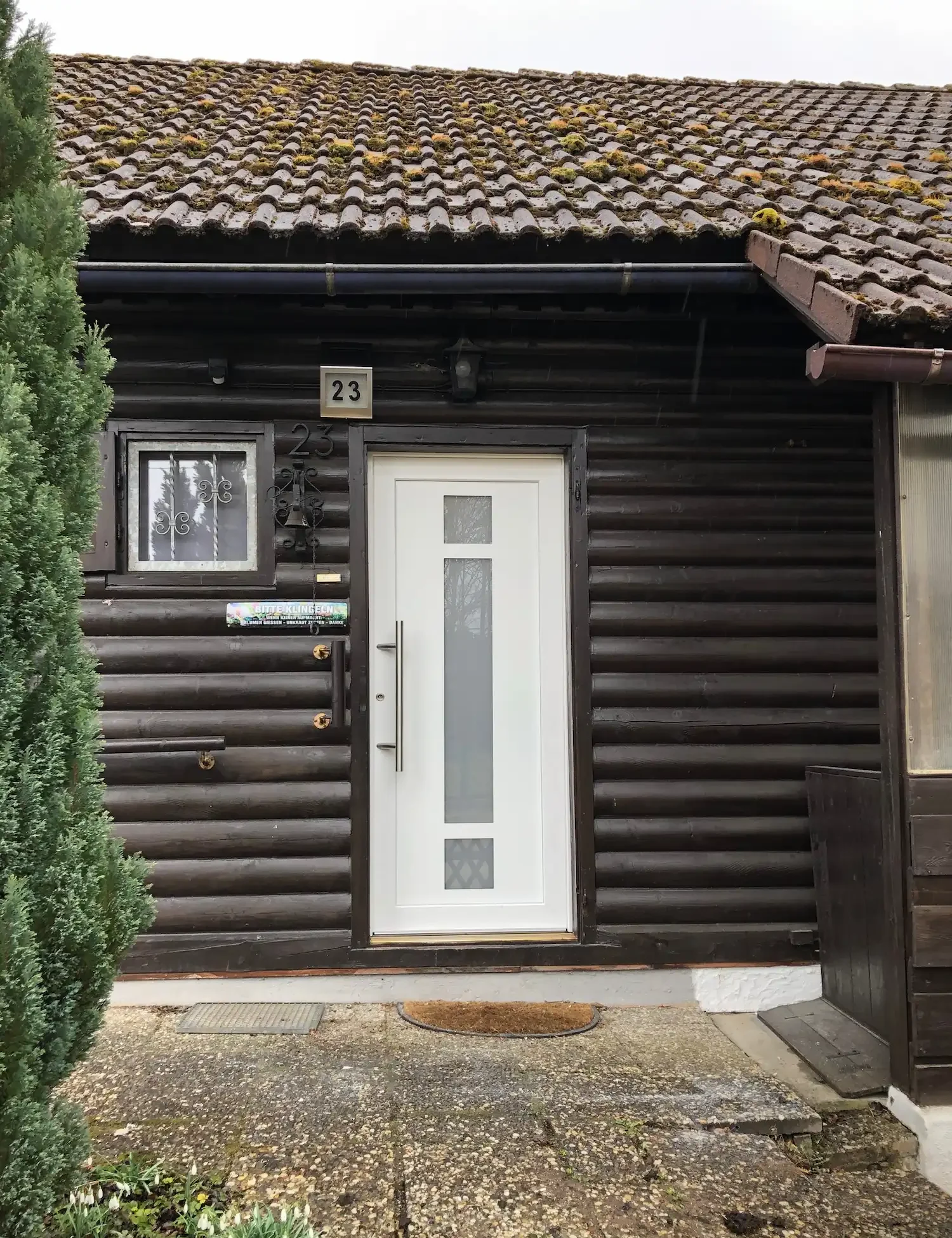 Eine weiße Haustüre mit 3 Glaselementen in der Mitte und einen eisernen Griff auf der linken Seite.
