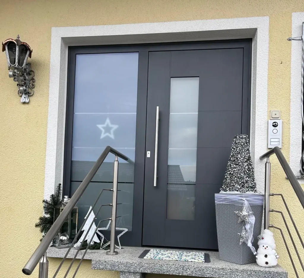 Eine neue Anthrazitfarbene Haustüre welche über mehrere Treppen und Geländer erreichbar ist.