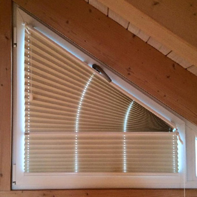 Ein geschlossnes Plissee an einen Gibelfenster mit Holzschrägen.