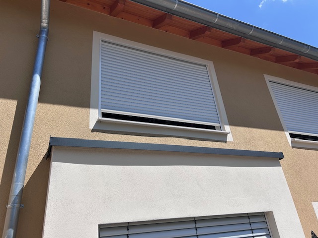 Heruntergelassener weißer Rollo eines Fensters im ersten Stock.